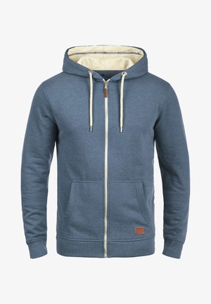 Blå hættetrøje med lynlås, lavet af blødt stof, med en kontrasterende cremefarvet foring, snore, to frontlommer og en læderlogo-patch.