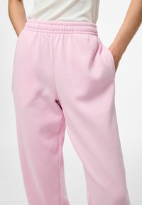 Roze joggingbroek van zacht materiaal, met een elastische tailleband en zijzakken. Gladde textuur met minimale naden, ontspannen pasvorm ontwerp.