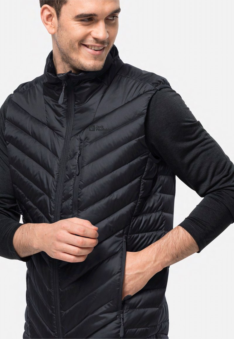 Schwarze Pufferweste mit einem Chevron-Steppdesign, ausgestattet mit einem hohen Kragen, einem Reißverschluss vorne und seitlichen Taschen. Logo auf der linken Seite sichtbar.