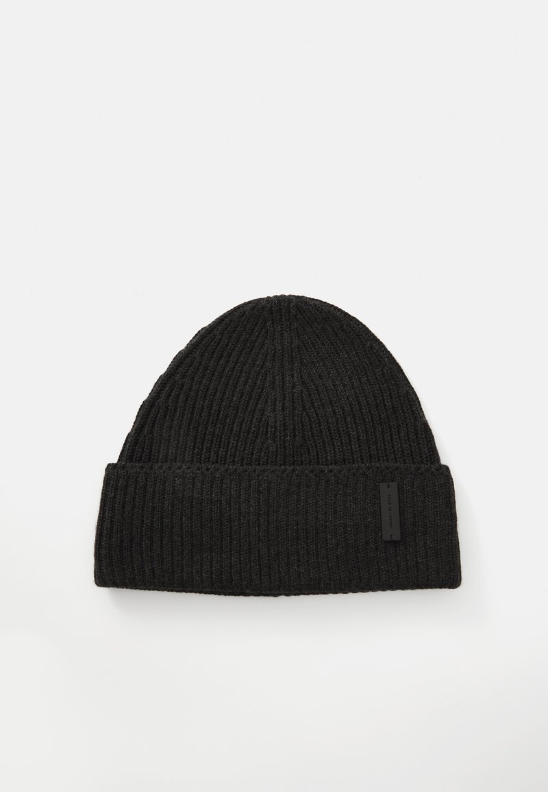 Gorro de malha canelada preto com bainha torcida e pequena etiqueta retangular da marca em fundo branco.