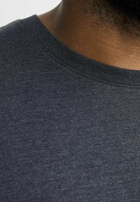 Mørk grå bomulds T-shirt med rund halsudskæring. Stoffet har en diskret tekstur og en klassisk pasform, med synlige sømme ved kraven.