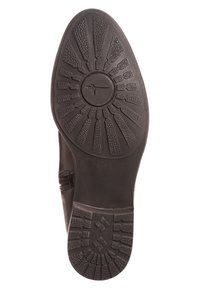 Suela de zapato de goma negra con un patrón de agarre texturizado que presenta diseños circulares y lineales, incluyendo un logo central.