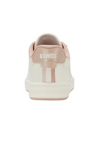 Zapatillas K-Swiss con un cuerpo de piel blanca, acentos rosa claro, detalle a rayas en el talón y un cuello de malla texturizada. Suela de goma plana.