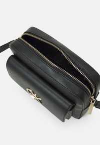 Borsa a tracolla in pelle nera con due scomparti con zip, dotata di hardware in tonalità oro e forma rettangolare con un'accattivante accentuazione del logo frontale.