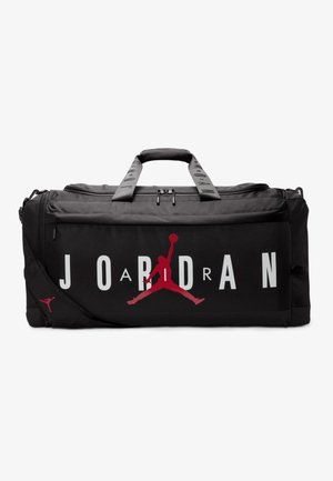 Sac de sport noir avec le logo rouge de Jordan et un grand texte blanc. Il dispose de poignées robustes, d'une bandoulière ajustable et d'une fermeture éclair.