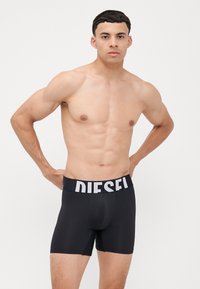 Boxers noirs avec un logo "DIESEL" blanc sur la ceinture élastique. Présente un design ajusté et un tissu doux et lisse.