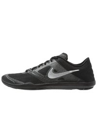 Black athletic shoe with a mesh upper, textured pattern, and silver Nike logo. Features flat laces and a rubber sole for grip.