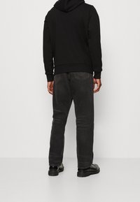 Svart hoodie med en känguruficka, bärs med mörkgrå jeans och svarta chunky skor. Outfit har en avslappnad, ledig passform.