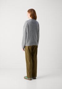 Gray wool sweater with a ribbed hem, paired with olive green wide-leg pants featuring side pockets. Model shown from the back.