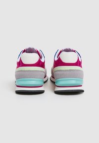 Zapatillas coloridas con un upper predominantemente rosa, acentos de ante gris, una franja verde y una suela translucida en aqua.