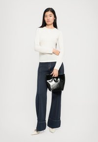 Valge pikkade varrukatega särk, mis on paaritatud tumesiniste laiad püksidega, millel on valged õmblused, ning läikiv must käekott. Koonilised valged kingad.