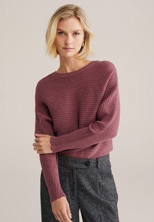 Gekürzter, gerippter Strickpullover in Burgunderrot mit weitem Rundhalsausschnitt und langen Ärmeln, kombiniert mit strukturierten grauen Hochbundhosen.