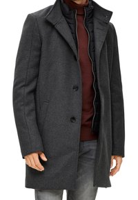 Cappotto di lana grigia con una vestibilità su misura, caratterizzato da un colletto a punte, due bottoni e uno strato interno trapuntato. Texture sottile e design elegante.