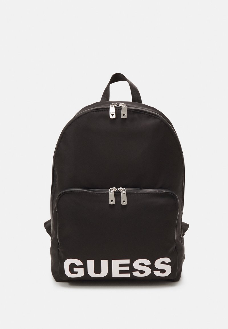 Zwarte nylon rugzak met het witte "GUESS" logo. Heeft een voorkant met ritsvak en dubbele ritslussen. Rond ontwerp met gewatteerde schouderbanden.