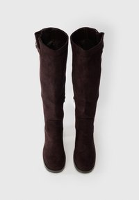 Térd magas burgundi színű zamak csizma sima textúrával, kerek orral és cipzáras részletekkel a külső oldalon.