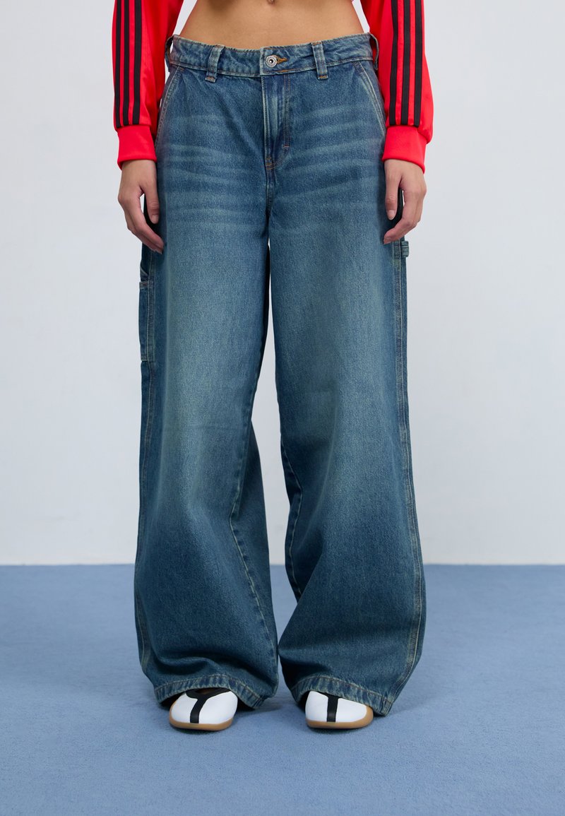 Weite blaue Jeans aus Denim mit hoher Taille, vorderem Knopfverschluss und Seitentaschen. Strukturierter Stoff mit Ausbleichungen und lockerer Passform.