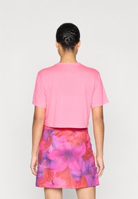 Κοντομάνικο ροζ μπλουζάκι συνδυασμένο με φούστα με λουλούδια που έχει μεγάλα ροζ και μωβ ανθισμένα σχέδια και εφαρμοστή μέση.