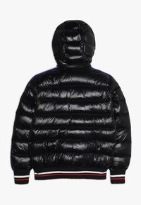 Manteau matelassé noir avec capuche, en matériau brillant, motif quilté horizontal et poignets côtelés avec des rayures rouges et blanches.