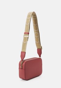 Czerwona skórzana torba na ramię o prostokątnym kształcie, teksturowanej powierzchni i beżowym pasku z powtarzającym się wzorem logo. Złote akcenty metalowe.