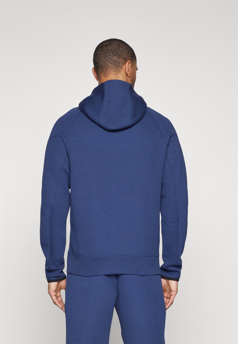 Felpa blu navy realizzata in tessuto morbido, con cappuccio regolabile, polsini a costine e vestibilità rilassata con interno foderato.