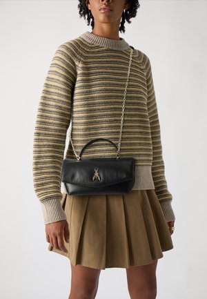 Schwarze Lederhandtasche mit einem oberen Griff und einer Kettenriemen, die mit einem metallischen Bienenakzent verziert ist. Tragen Sie sie zu einem gestreiften Pullover und einem gefalteten Rock.