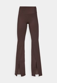 Brune flared leggings i myk stoff med høy midje og sidespalter i kanten. Har flatlock-sømmer for en jevn passform.