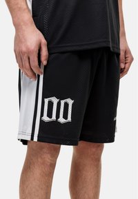 Zwarte basketbalschoenen met zijstrips in het wit, gemaakt van meshstof. Kenmerkt zich door een witte "00" graphic op het voorste linkerpijp.
