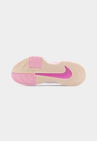 Σόλα ενός μπεζ και ροζ παπουτσιού Nike με ανάγλυφο ζιγκ-ζαγκ μοτίβο στην επιφάνεια και εξέχον ροζ λογότυπο Nike Swoosh στο κέντρο.