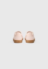 Sneakers in pelle rosa con una texture liscia, talloni rotondi e suole in gomma naturale, caratterizzati da una sottile logo sul tallone.