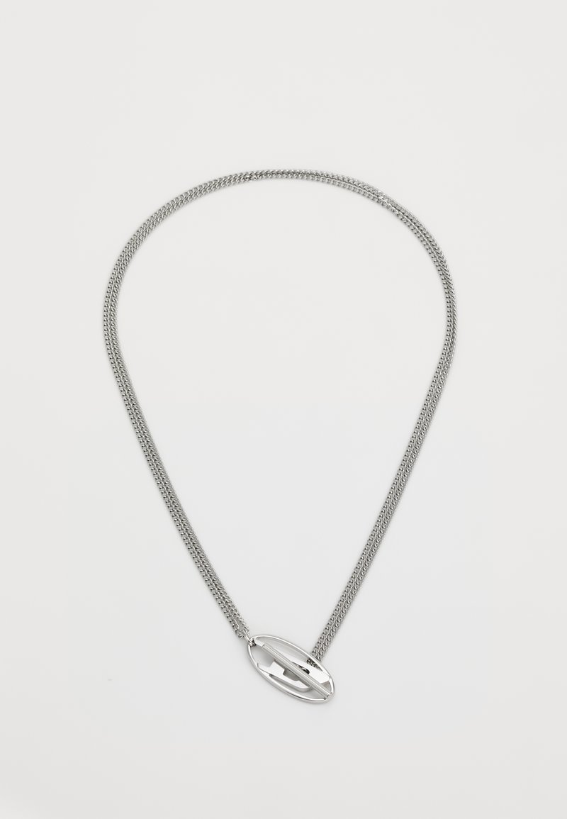 Sølvkjede med teksturert kjede og en glatt, oval pendant med detaljert utskjæring i midten.