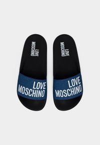 Ζευγάρι μαύρες σαγιονάρες τύπου slide με μπλε υφασμάτινα λουριά, κάθε λουρί και πέλμα τυπωμένα με λευκό κείμενο "LOVE MOSCHINO".