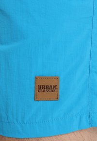 Svijetloplave platnene šorceve sa smešnim kožnim ušicama s oznakom "URBAN CLASSICS" na rubu, s suptilnom teksturom i ravnim krojem.