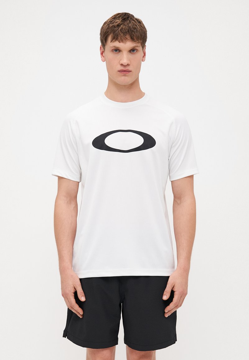 Weißes Sport-T-Shirt mit kurzen Ärmeln und einem schwarzen ovalen Logo auf der Brust. Der Stoff wirkt glatt und leicht.