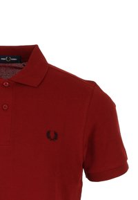 Polo rouge en coton avec une finition texturée. Présente un logo noir brodé sur la poitrine gauche et un col classique.