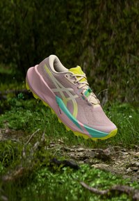 Sapatilha de corrida rosa e bege com parte superior em malha respirável, detalhes em turquesa e amarelo, sola texturizada e design elegante.