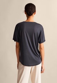 Dunkelgraues kurzärmeliges T-Shirt mit lockerem Schnitt und überschnittenen Schultern. Weiches Material mit Rundhalsausschnitt und leicht abgerundetem Saum.
