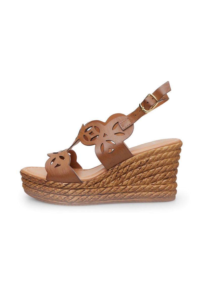 Sandale en cuir brun à semelle compensée avec des découpes florales, sangle de cheville réglable et plateforme texturée en corde tissée.