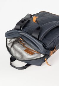 Zaino blu navy con design trapuntato, dettagli in pelle beige e un ampio interno foderato con un motivo a griglia grigia e chiusura a zip.