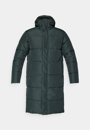 Dunkelgrüne Pufferjacke mit langem Schnitt, hochstehendem Kragen, Druckknöpfen vorne und Seitentaschen. Glatte, gesteppten Textur.