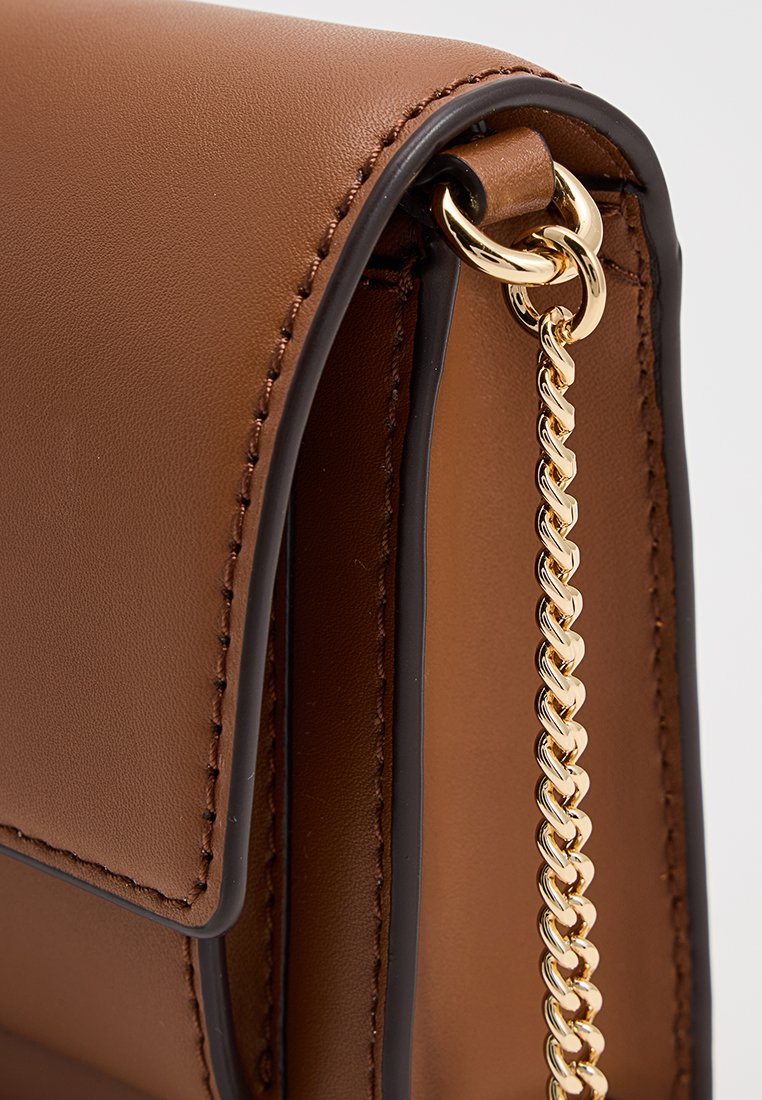 Sac à main en cuir marron avec une chaîne en or, texture lisse et coutures contrastantes le long des bords. Fermeture avec un rabat.