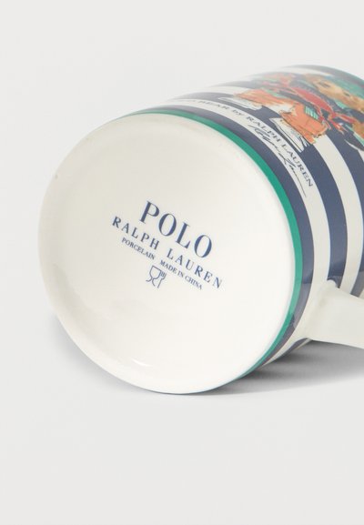 Fehér kerámia bögre kék és zöld csíkokkal, Polo Ralph Lauren logóval és egy ruhás medvét ábrázoló illusztrációval.