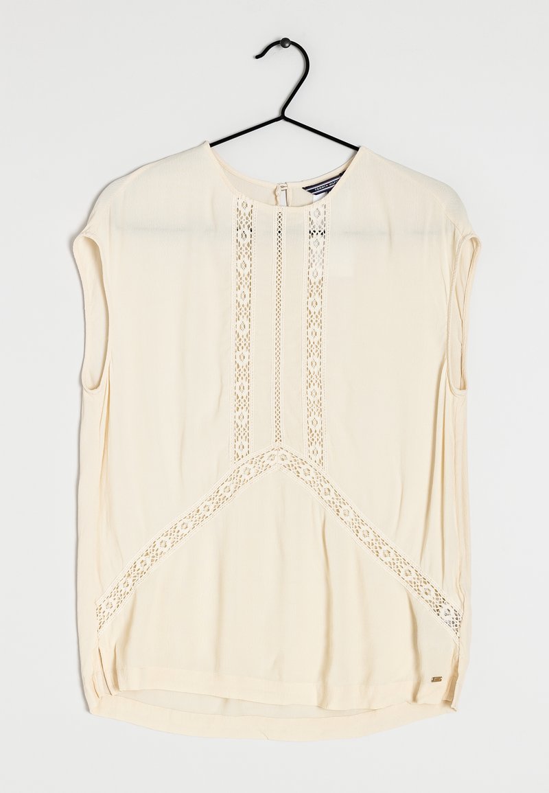 Short-sleeve cream blouse with lace accents, round neckline, and a curved hem. Features vertical lace detailing down the front panel.