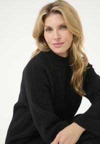 Maglione nero a collo alto con maniche lunghe, caratterizzato da un motivo a maglia testurizzata e una vestibilità rilassata. Tessuto morbido, design minimalista.