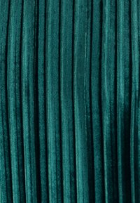 Tela de terciopelo verde azulado con pliegues verticales, creando una apariencia texturizada con un suave brillo y una rica profundidad de color.