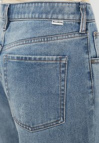 Lys blå dongeribukser med falmet finish, kontrastsøm, en liten Billabong-merkelapp og klassisk baklommedesign.