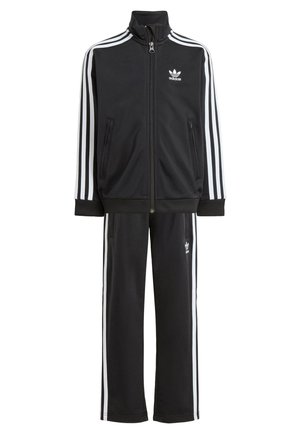 Svart zip-up jacka och matchande byxor, med vita tre-stripes detaljer och en Adidas-logotyp på båda plaggen. Gjorda av ett mjukt tyg.