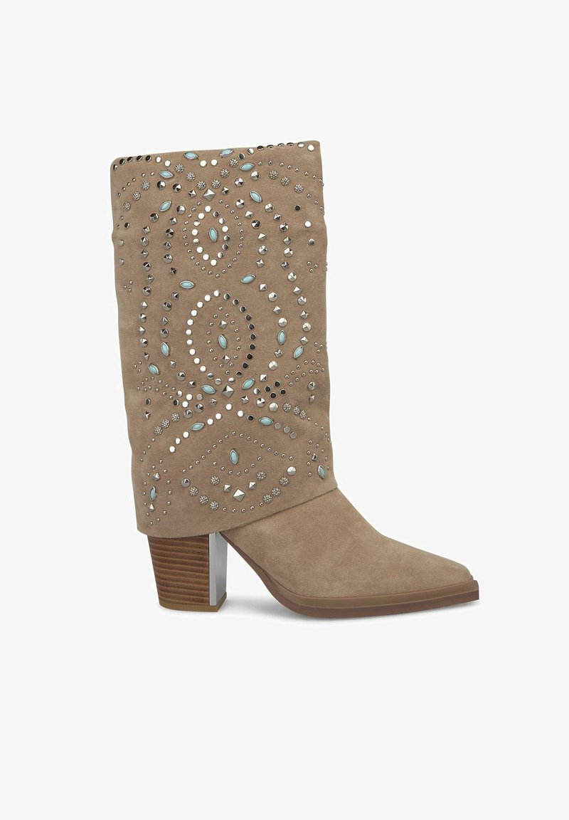 Botte mi-mollet en daim couleur fauve, talon bloc, bout pointu, avec des pierres bleues décoratives et des clous argentés formant des motifs complexes.