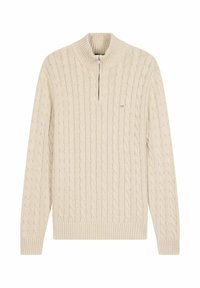 Pull en tricot beige avec col zippé mi-hauteur, poignets et ourlet côtelés, affichant des motifs texturés sur l'ensemble du tissu.