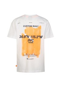Wit katoenen t-shirt met een oranje verfspattenontwerp, vetgedrukte zwarte tekst met de woorden "CUSTOM BUILT 30.8°N 115.2°W INC" en merklogo.