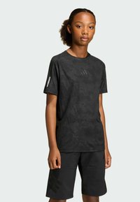 Black athletic t-shirt with camouflage pattern and reflective logo. Paired with black shorts featuring a subtle logo design. Smooth fabric texture.